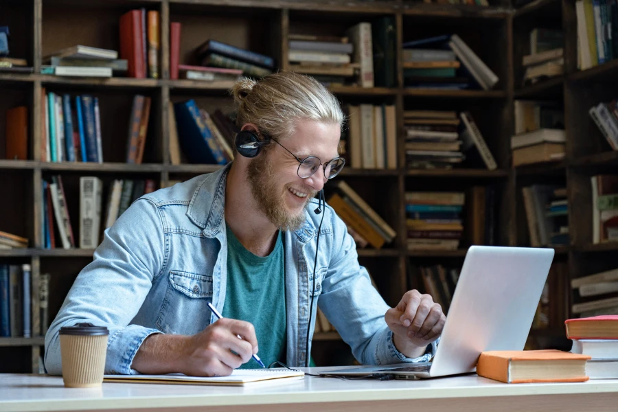 Joven en una biblioteca aprendiendo en una computadora portátil