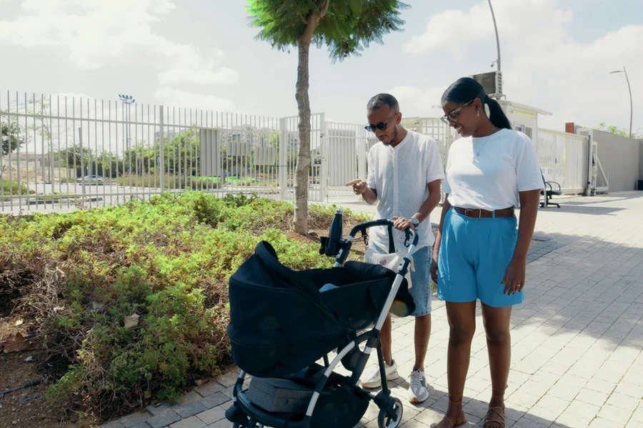 A woman and man with a black baby stroller
