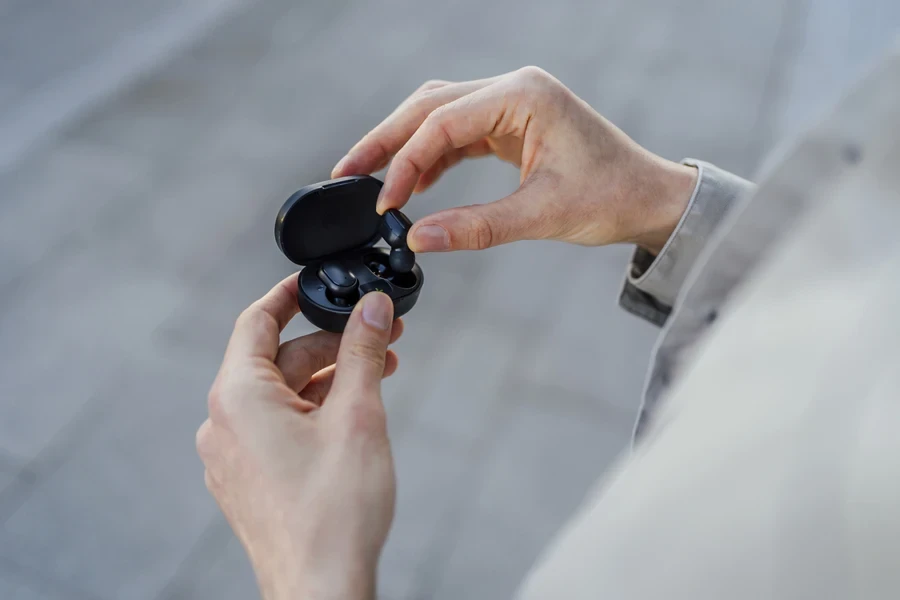 Anonymous man holding black waterproof wireless earbuds