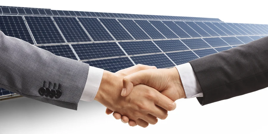 Investor dan pengusaha berjabat tangan di ladang tenaga surya