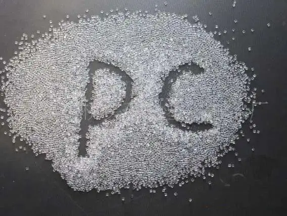 Polycarbonate (PC) granules arranged in the shape of 'PC' letters on a dark surface