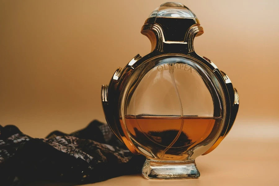 A clear glass perfume bottle with a brown background