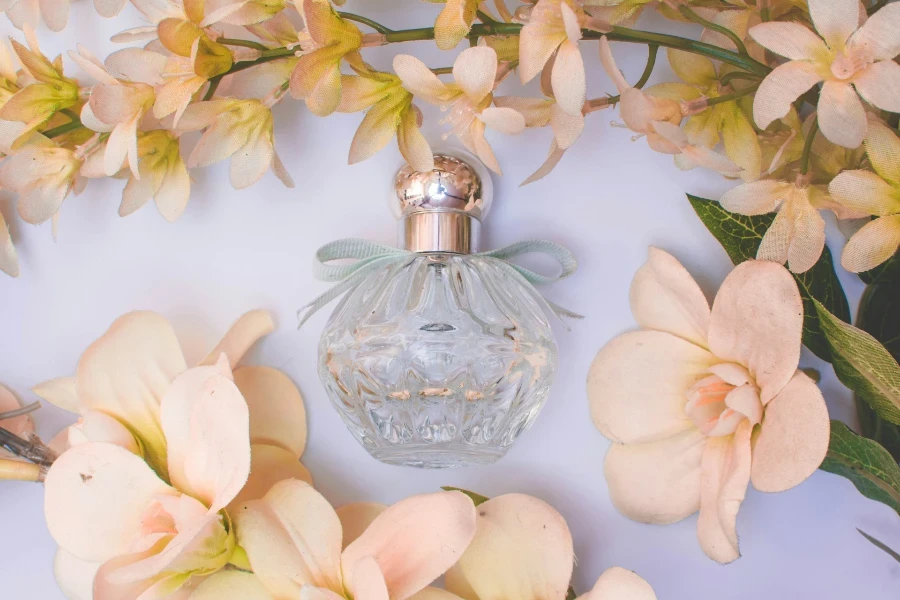 Un frasco de perfume de vidrio transparente con flores.