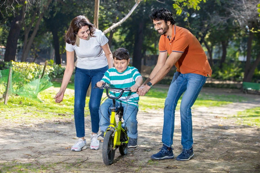 a couple teaches their son to ride a balance bike