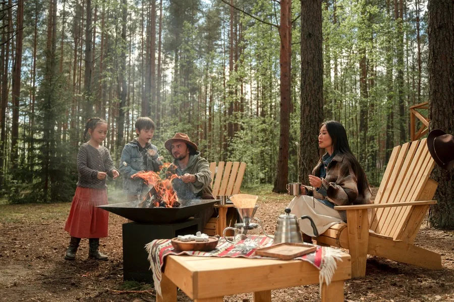 A family using an outdoor fire pit during a camping trip