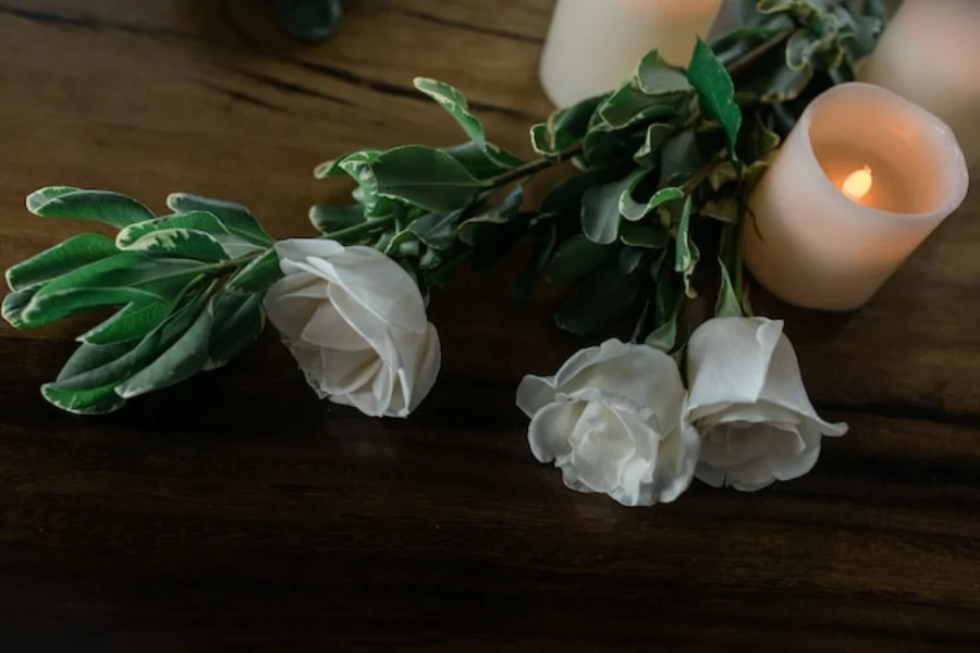 A flameless candle with a bunch of flowers on a table