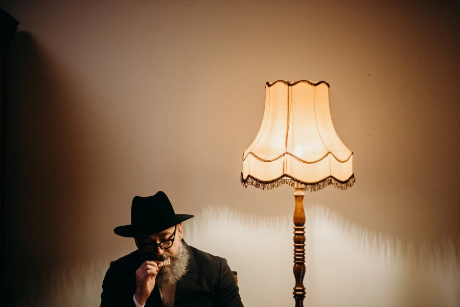 A man eating beside a traditional floor lamp
