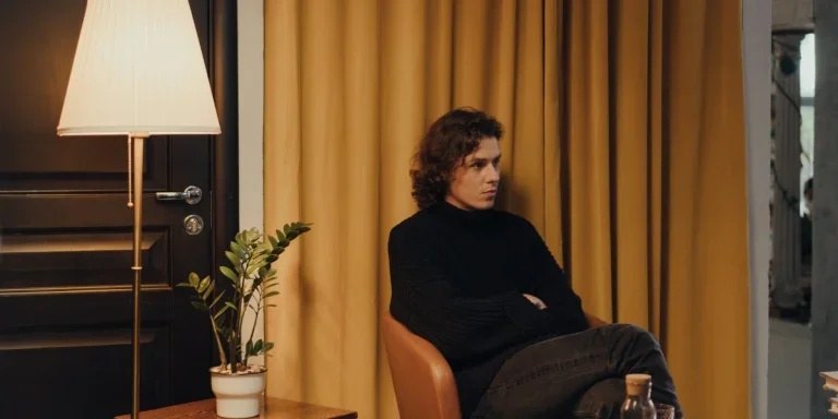 A man sitting on a seat next to a floor lamp