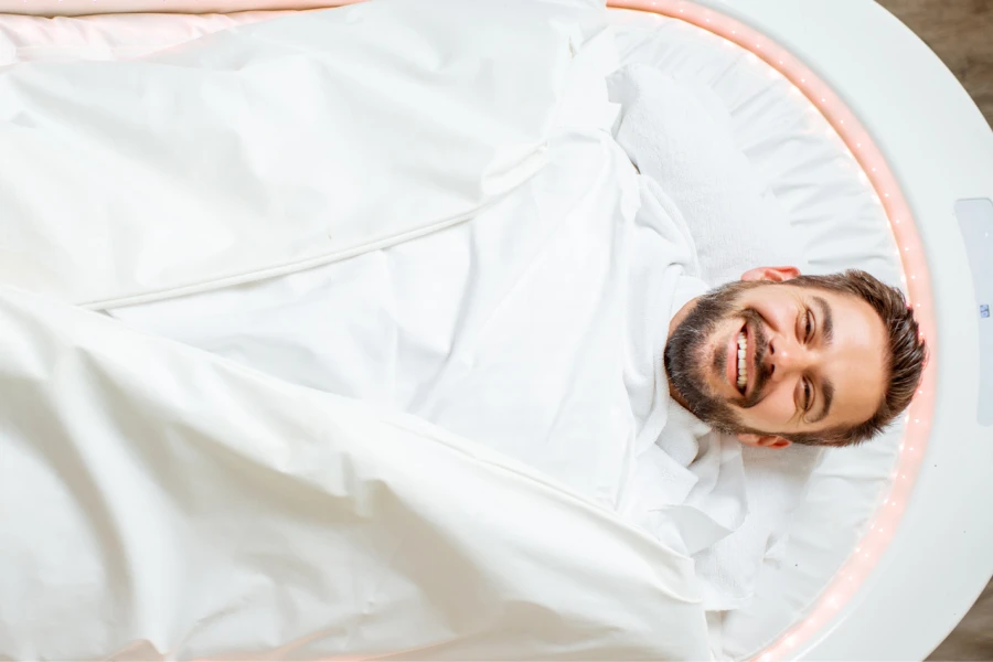 A smiling man tucked in a spa capsule