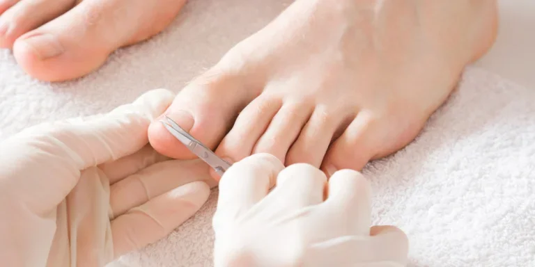 Beautician trimming client’s toe nails with manicure scissors