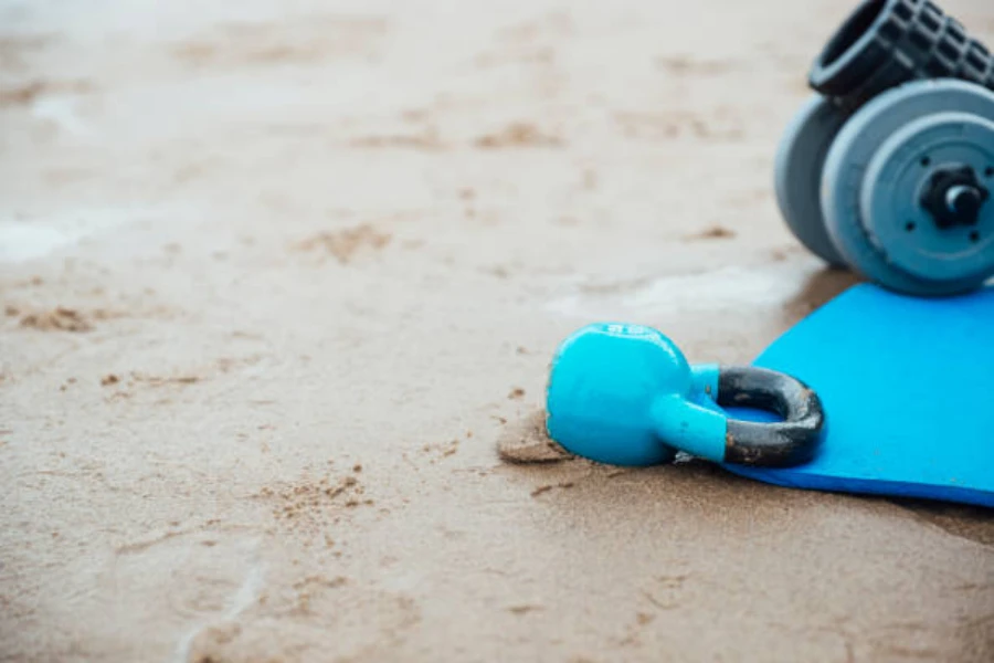 Синяя гиря сидит рядом с синим ковриком на песчаном пляже