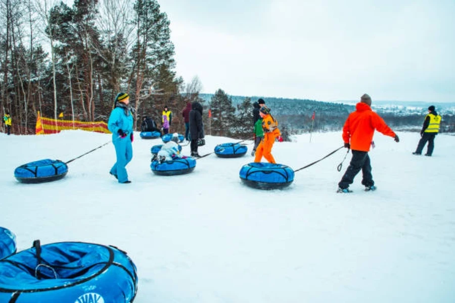 Blue snow tubes being pulled through snow in mountain area