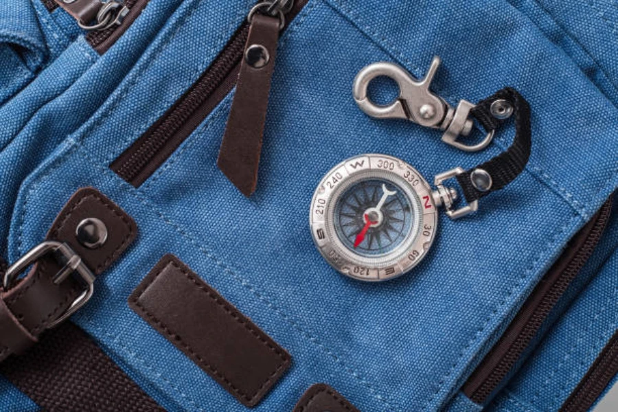 Button compass attached to keychain sitting on denim bag