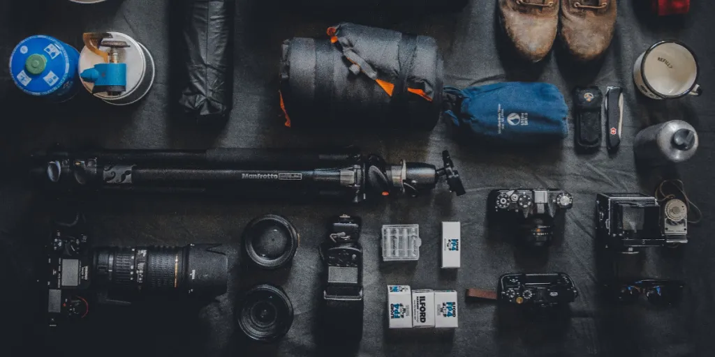 Camping equipment and cameras laid out on a black surface