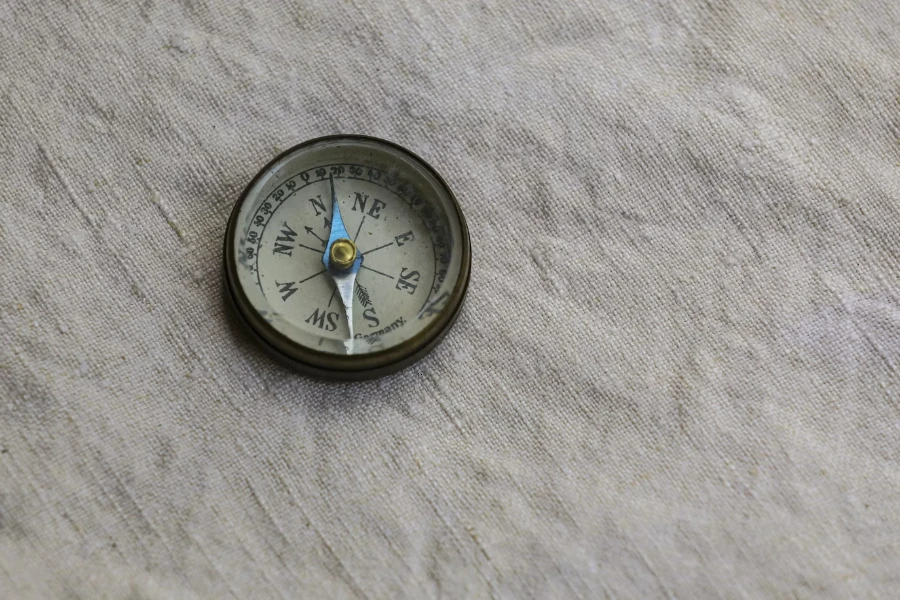 Classic small compass sitting on gray linen sheet