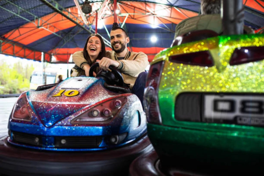 Couple steering colorful bumper car in enclosed space