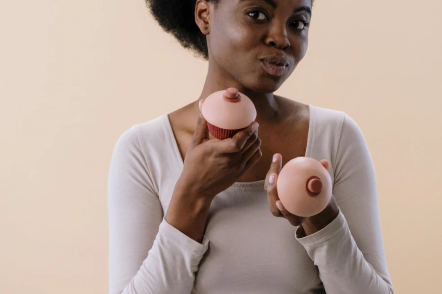 Dark-skinned woman holding two breast forms