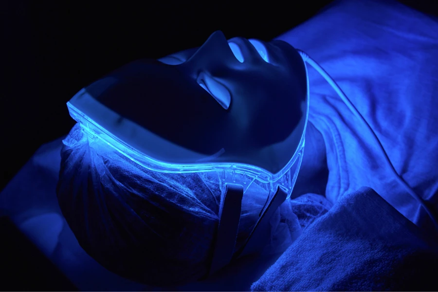 Female client inside an LED light therapy machine with mask