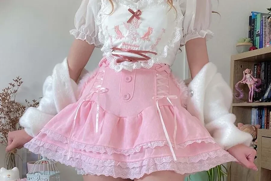 Ragazza con una minigonna rosa decorata con pizzo e nastri