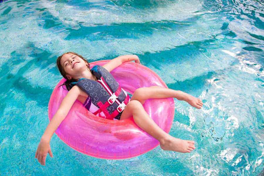 Girl using floating donut ring while wearing floral life jacket