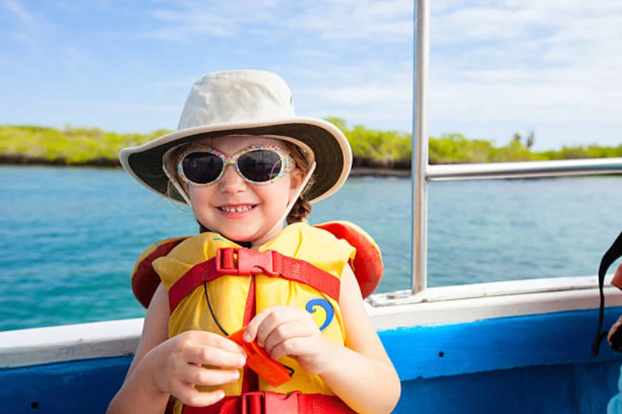 Girl wearing yellow and red life jacket with sun hat