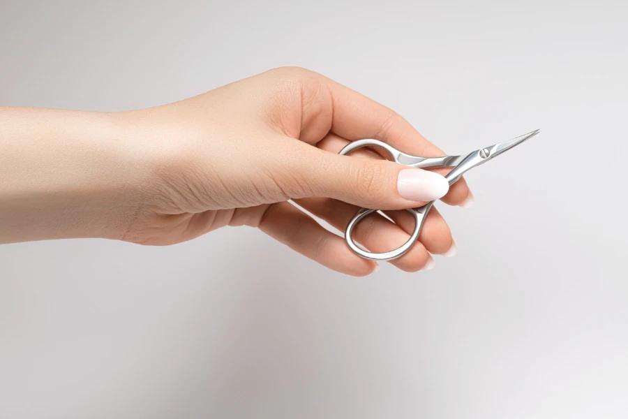 Hand holding a pair of steel manicure scissors