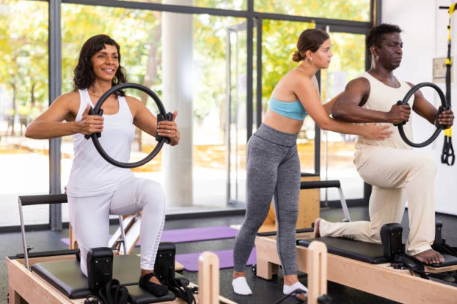 Man and woman using black pilates rings during pilates class