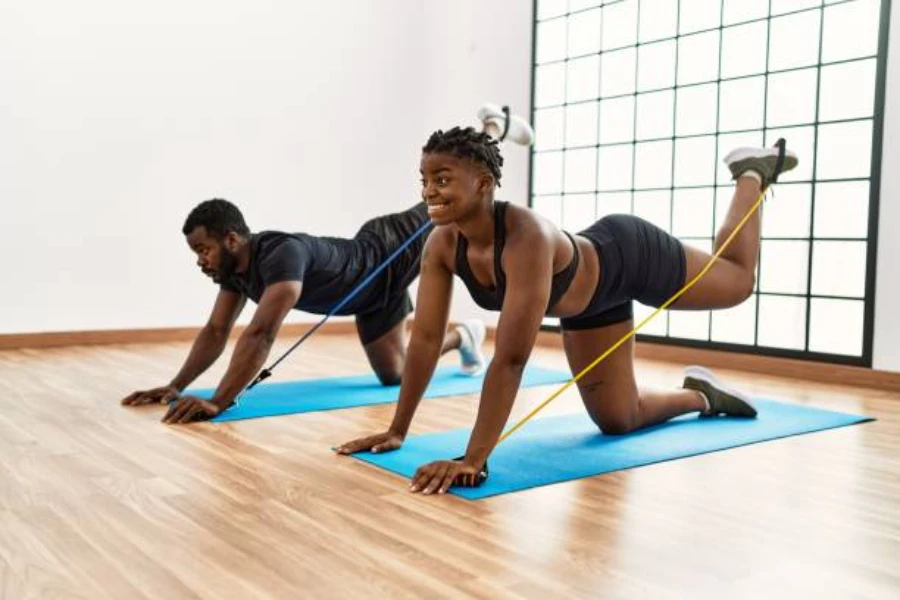 Man and woman using pilates resistance bands on mat