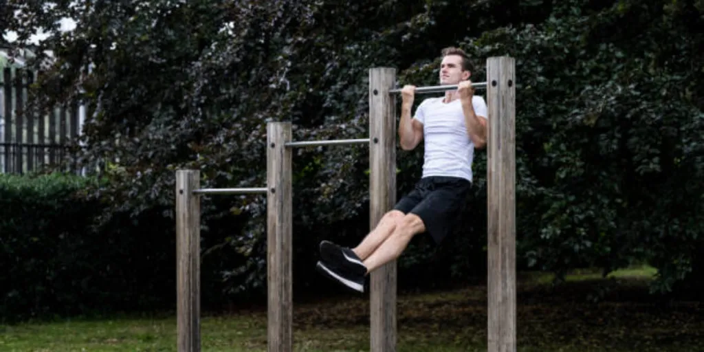 Man holding a pull up on outdoor bar in park