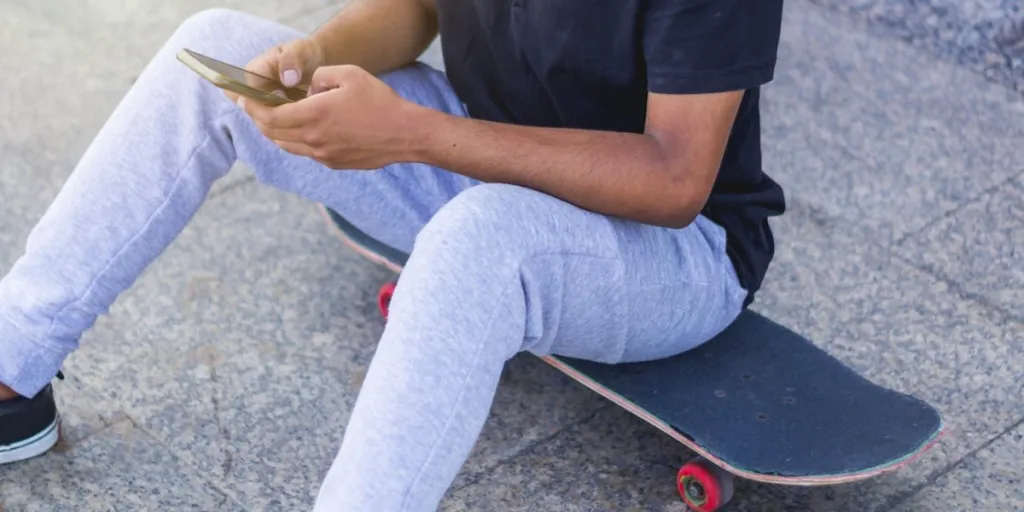 Man in gray sweatpants sitting on a skateboard