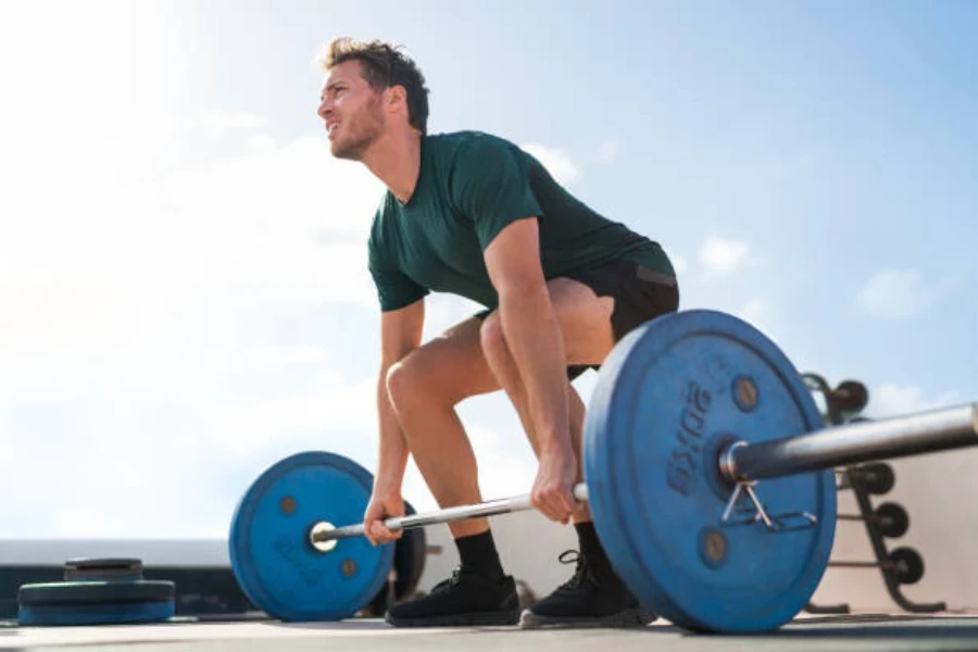 Man lifting outdoor barbell on rooftop during sunny day