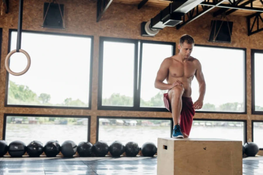 Homme debout avec une jambe sur une boîte plyo en bois