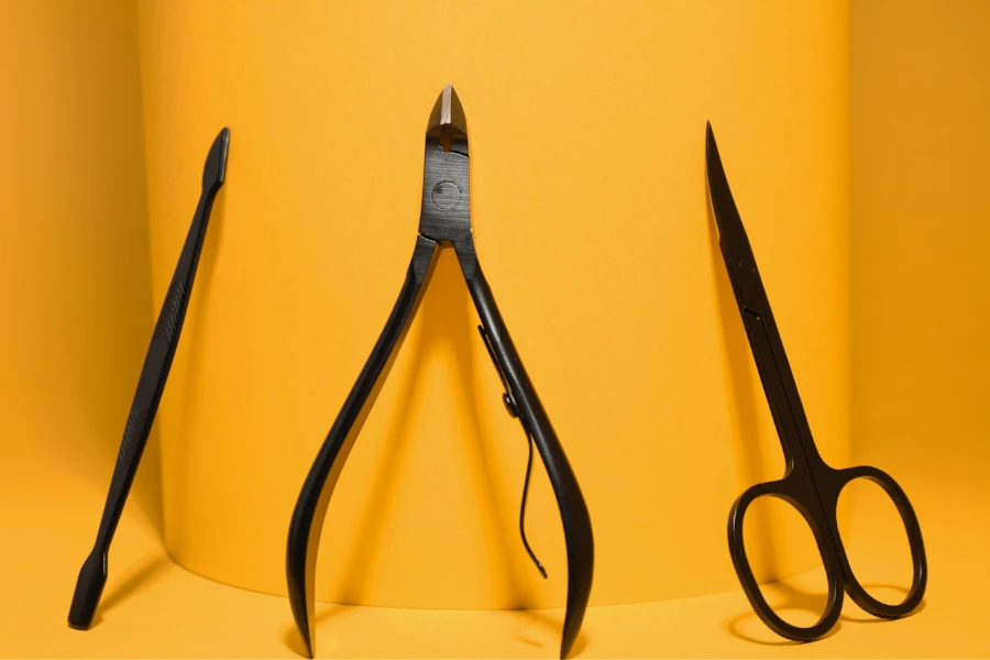 Маникюрные ножницы и другие инструменты на желтом фоне