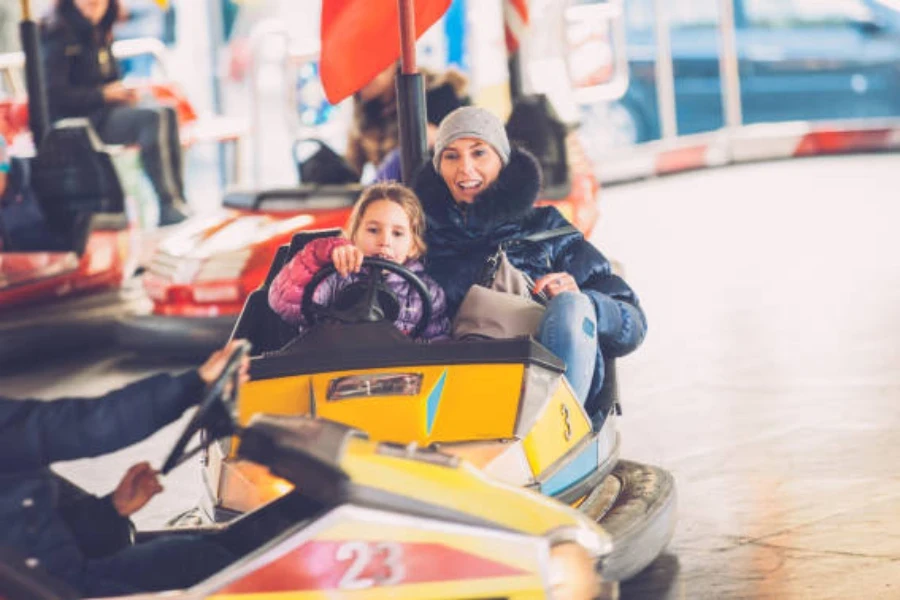 Mère et enfant montant une auto tamponneuse en hiver