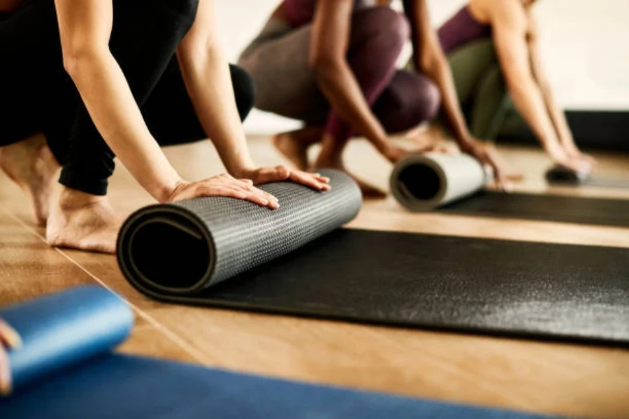 People in pilates class rolling up pilates mats on floor