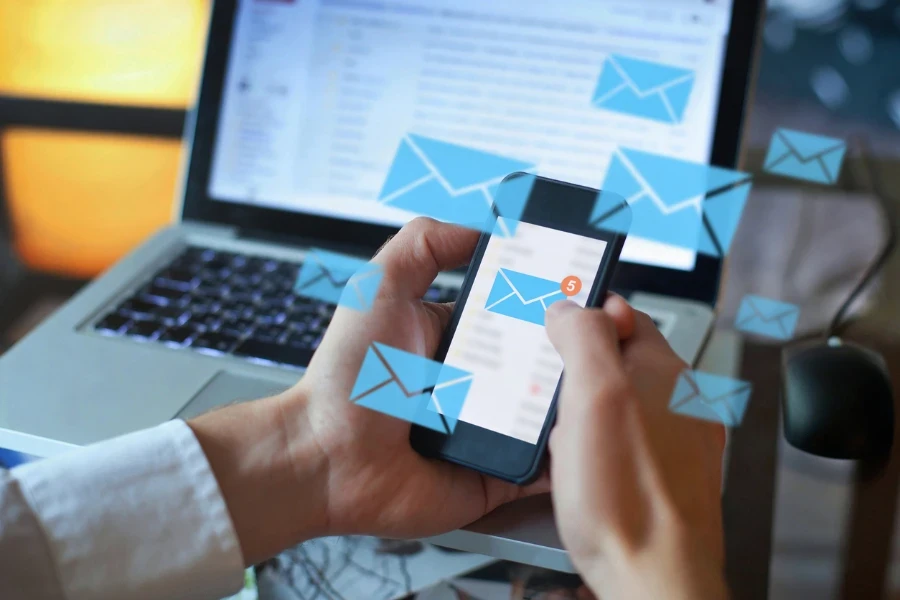 Person holding a smartphone with a number of mail symbols floating