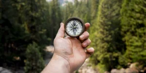 Person holding up best hiking compass with view of mountains