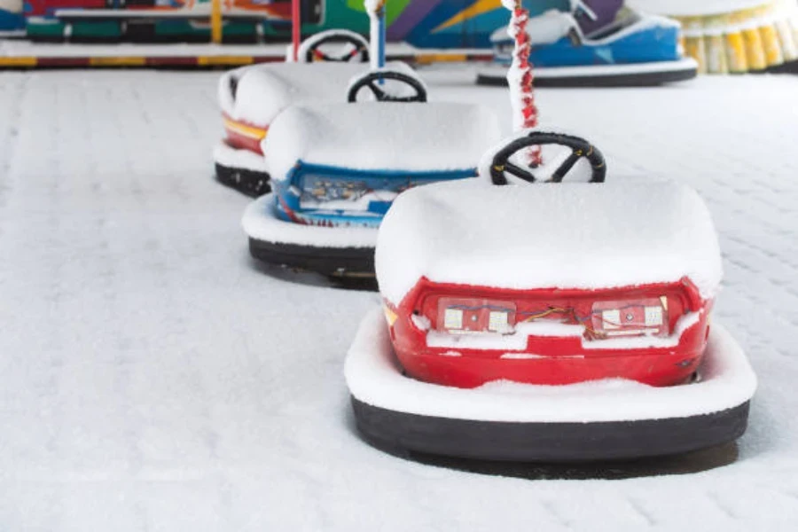 Fila de autos chocadores alineados y cubiertos de nieve