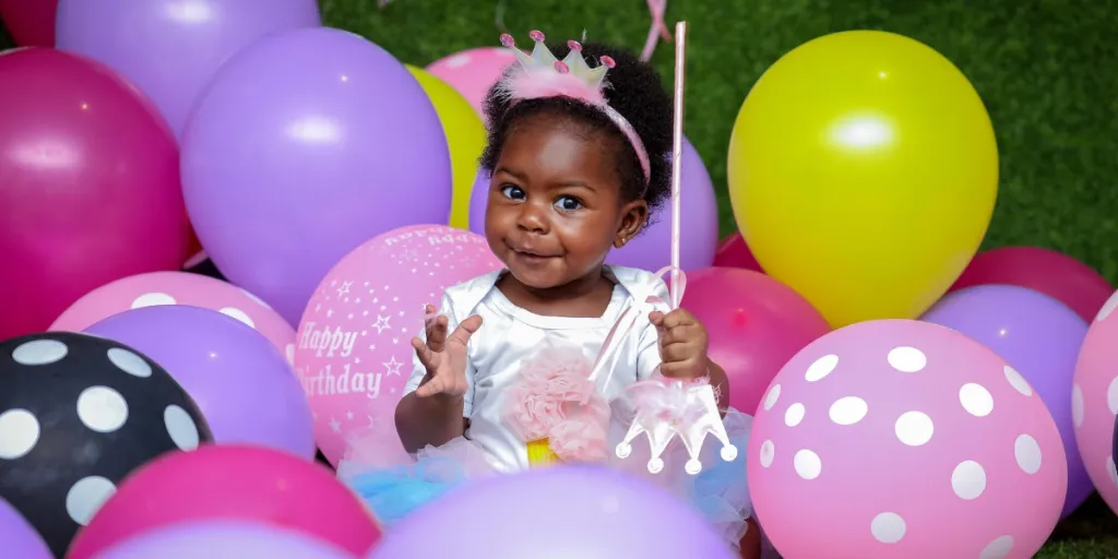 Smiling kid amidst birthday balloons