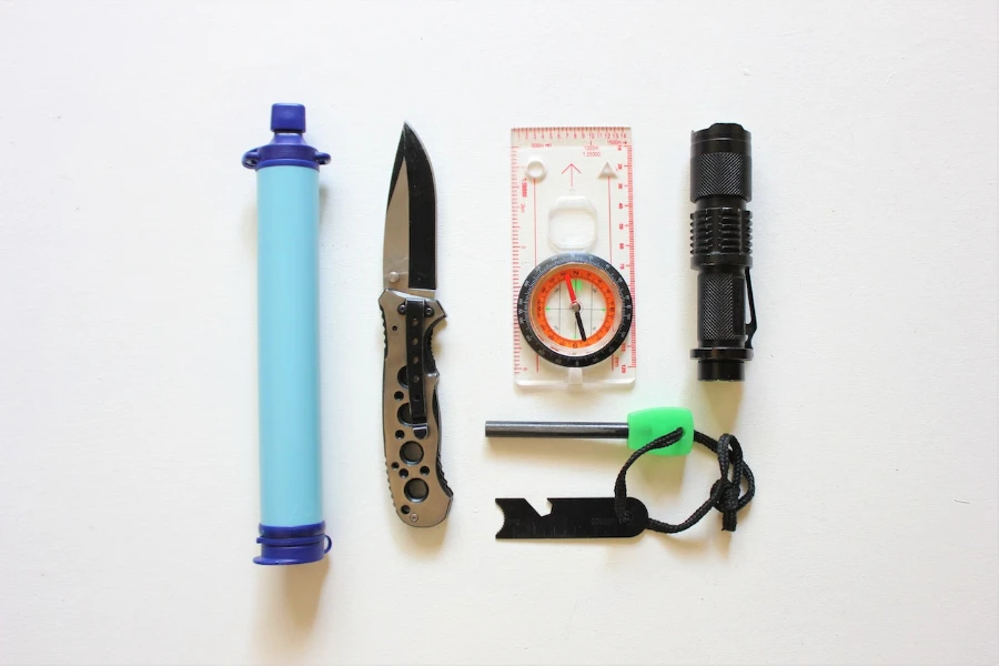 Survival kit with water filter, knife, compass and flash light on a white background