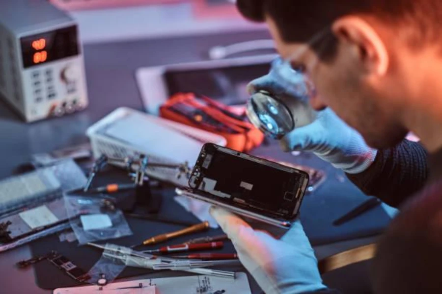 Technician examining mobile phone parts in a workshop
