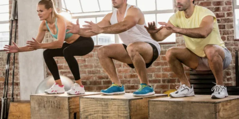 Three adults holding a squat on top of plyo boxes