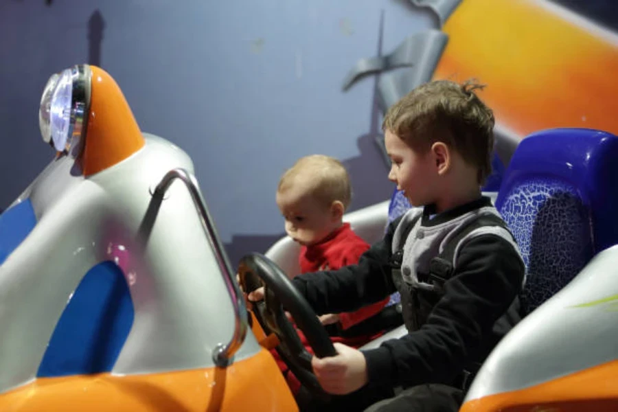 Dos niños sentados dentro de un gran auto chocador de hielo con luces