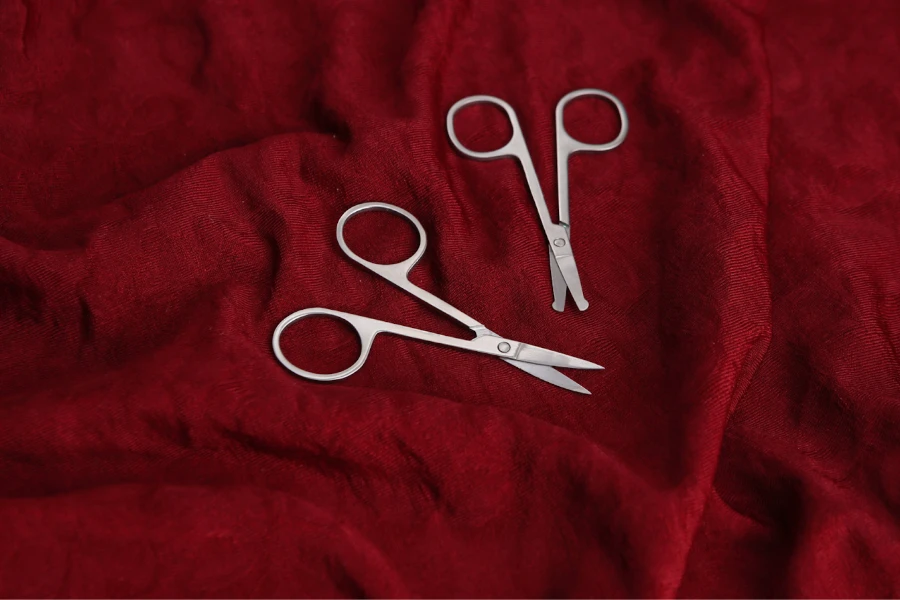 Two pairs of manicure scissors on a red platform