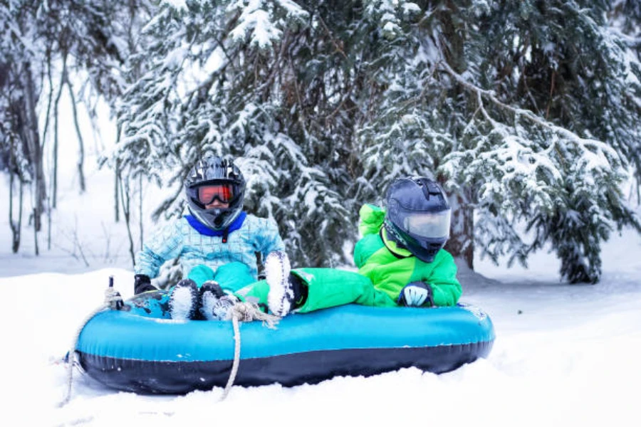 Two people sitting in double snow tube with helmets on