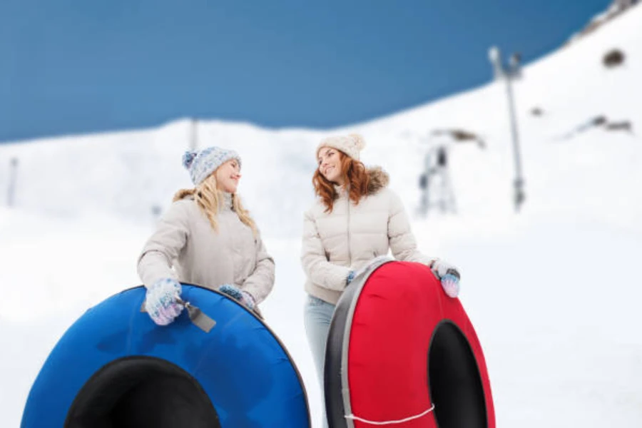 Two women holding a blue and red inflatable snow tube