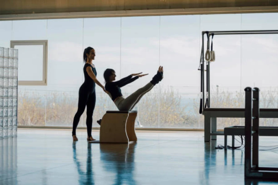 Dos mujeres en clase de pilates usando equipo para estirar