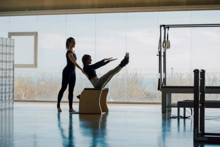 Two women in pilates lesson using equipment for stretching