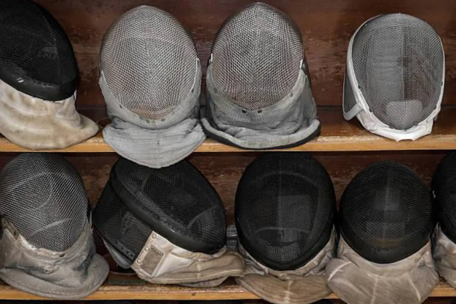 Various fencing masks on a wooden shelf