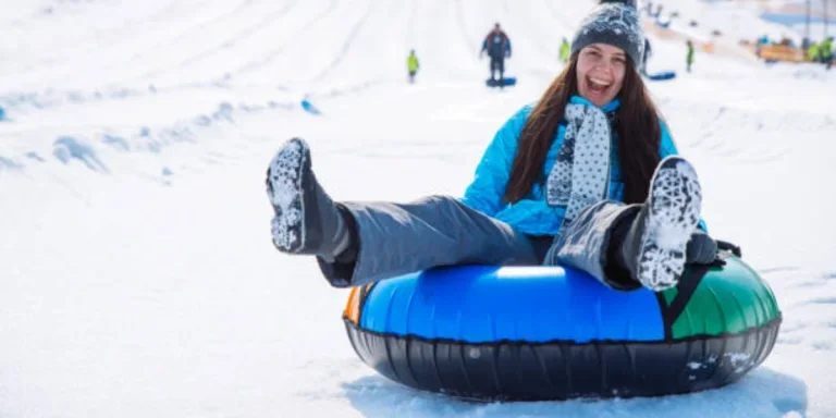 Woman at base of snowy hill sitting in snow tube